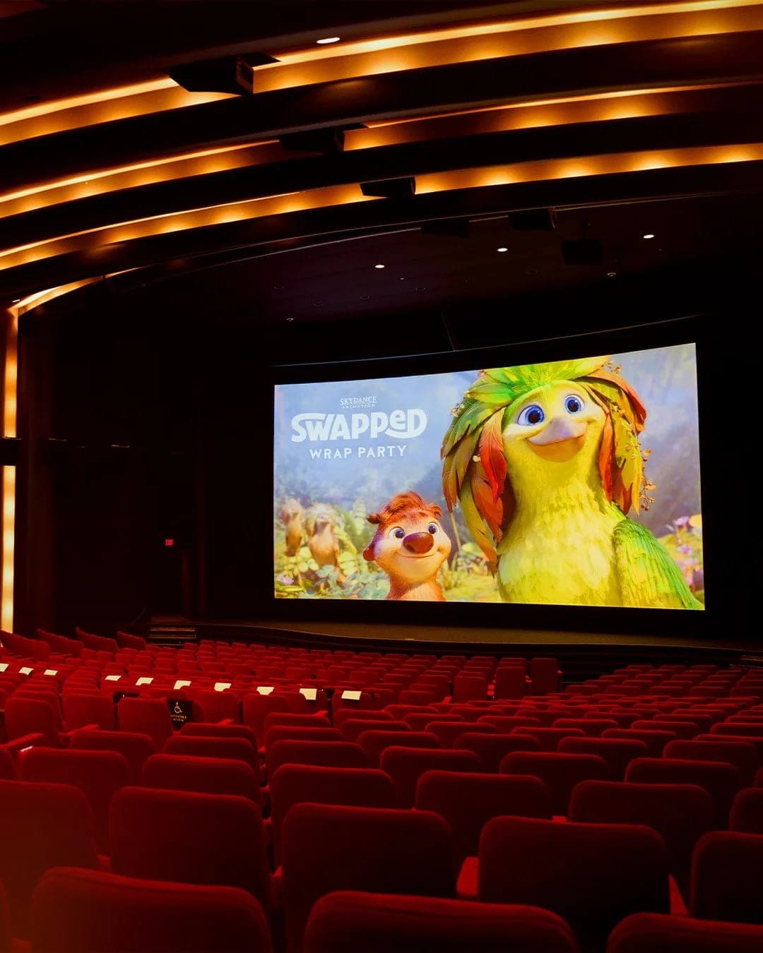 The film's title card on the screen of an empty red-seated cinema before the premiere
