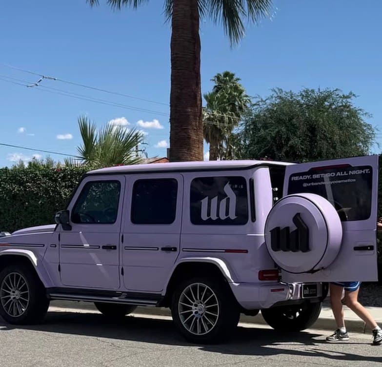 A lilac G-Wagon wrapped in the Urban Decay mark, parked under palm trees for a Coachella activation.
