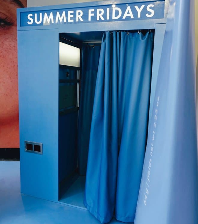 A Summer Fridays photo booth with blue curtains.