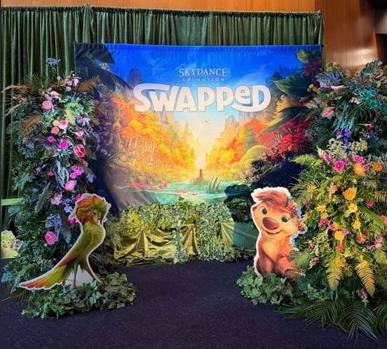 The Swapped premiere backdrop: a painted forest scene framed in flowers, with two of the film’s characters standing in front.