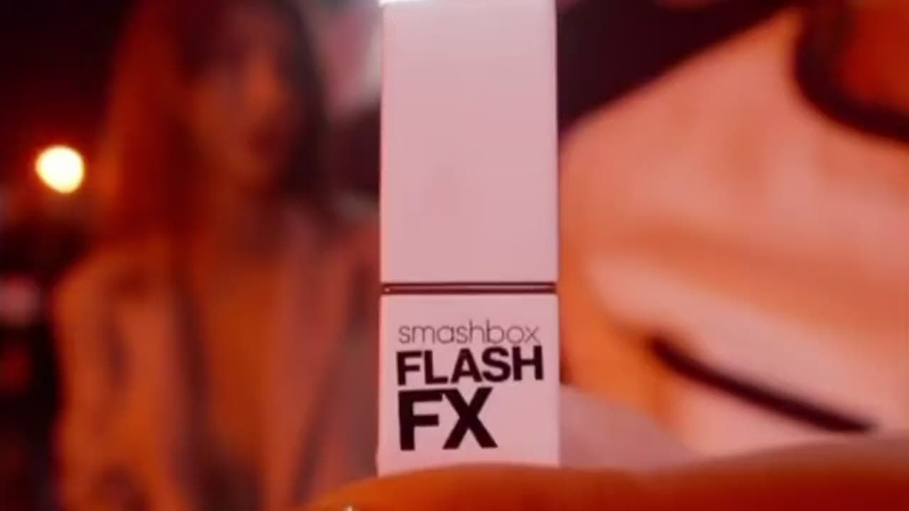 A Smashbox Flash FX lipstick held up in the crowd at the SBX Rated launch, the room washed red.
