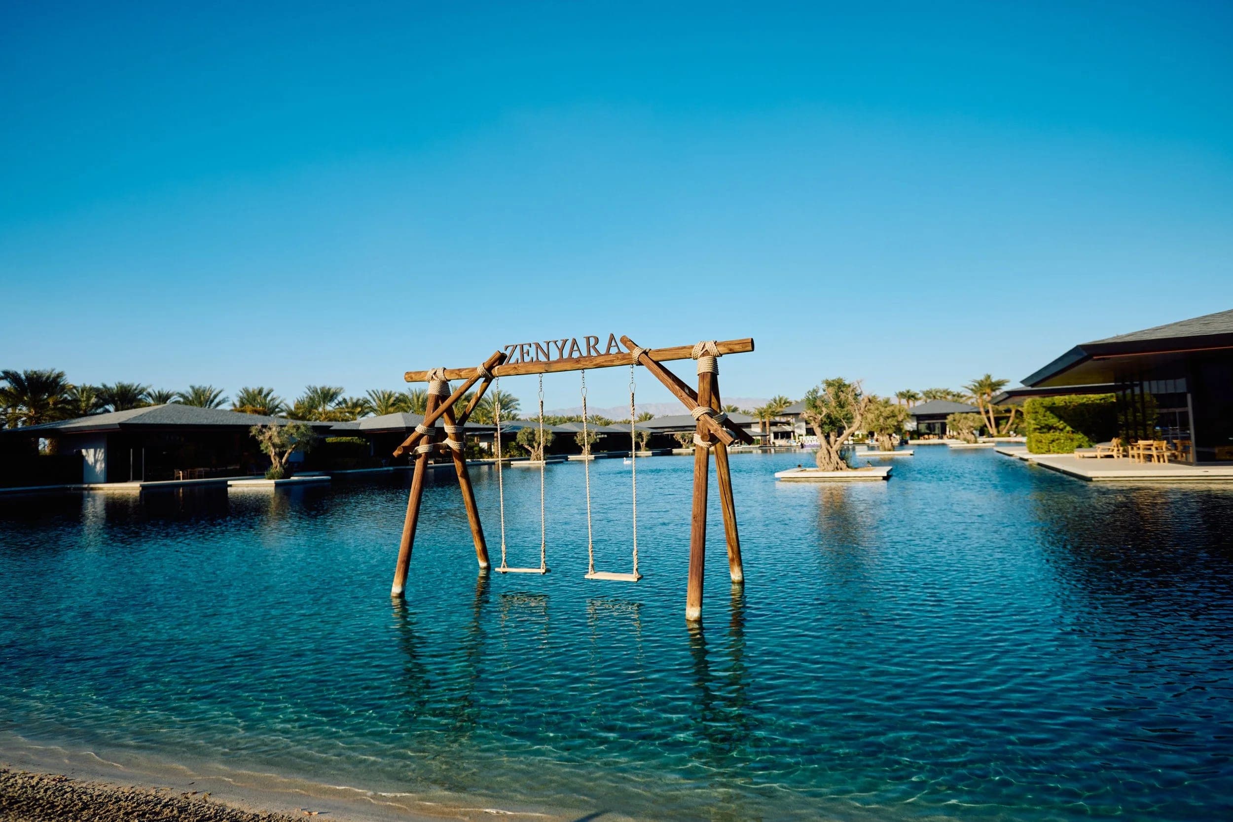 A wooden swing standing in the shallow end of the estate pool, the property spread out behind
