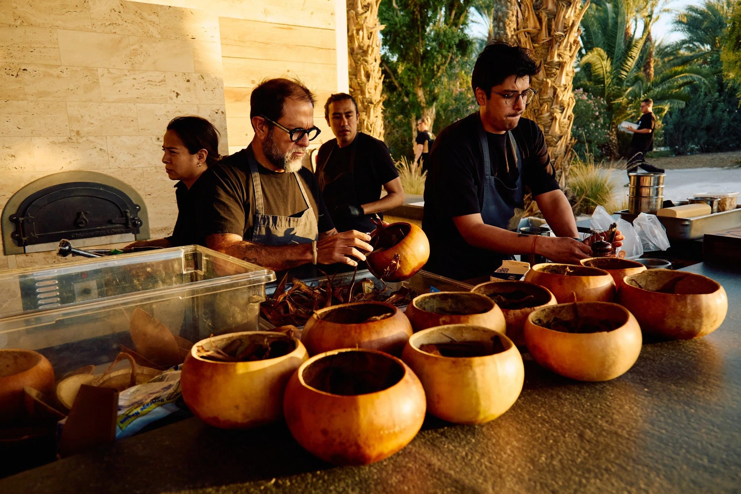 Kitchen crew arranging rows of clay cooking pots along the counter before service