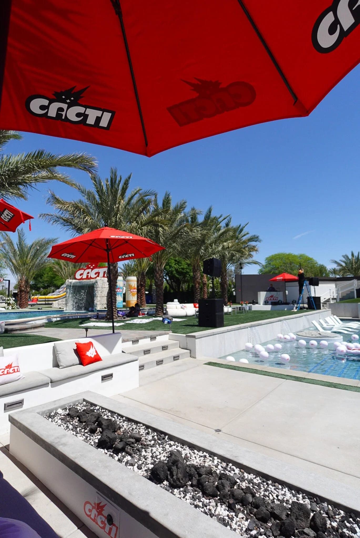 A red Cacti-branded umbrella shading the pool deck at the Cacti pool party