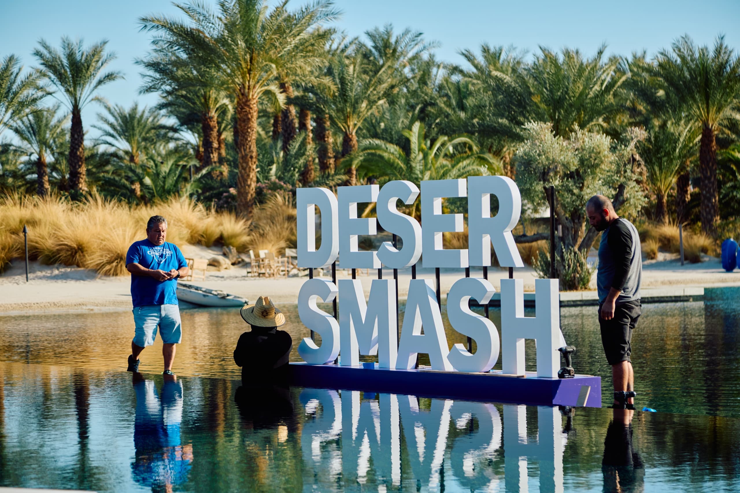 The DESERT SMASH letters standing in the water at Zenyara Estate, with the desert hills behind.
