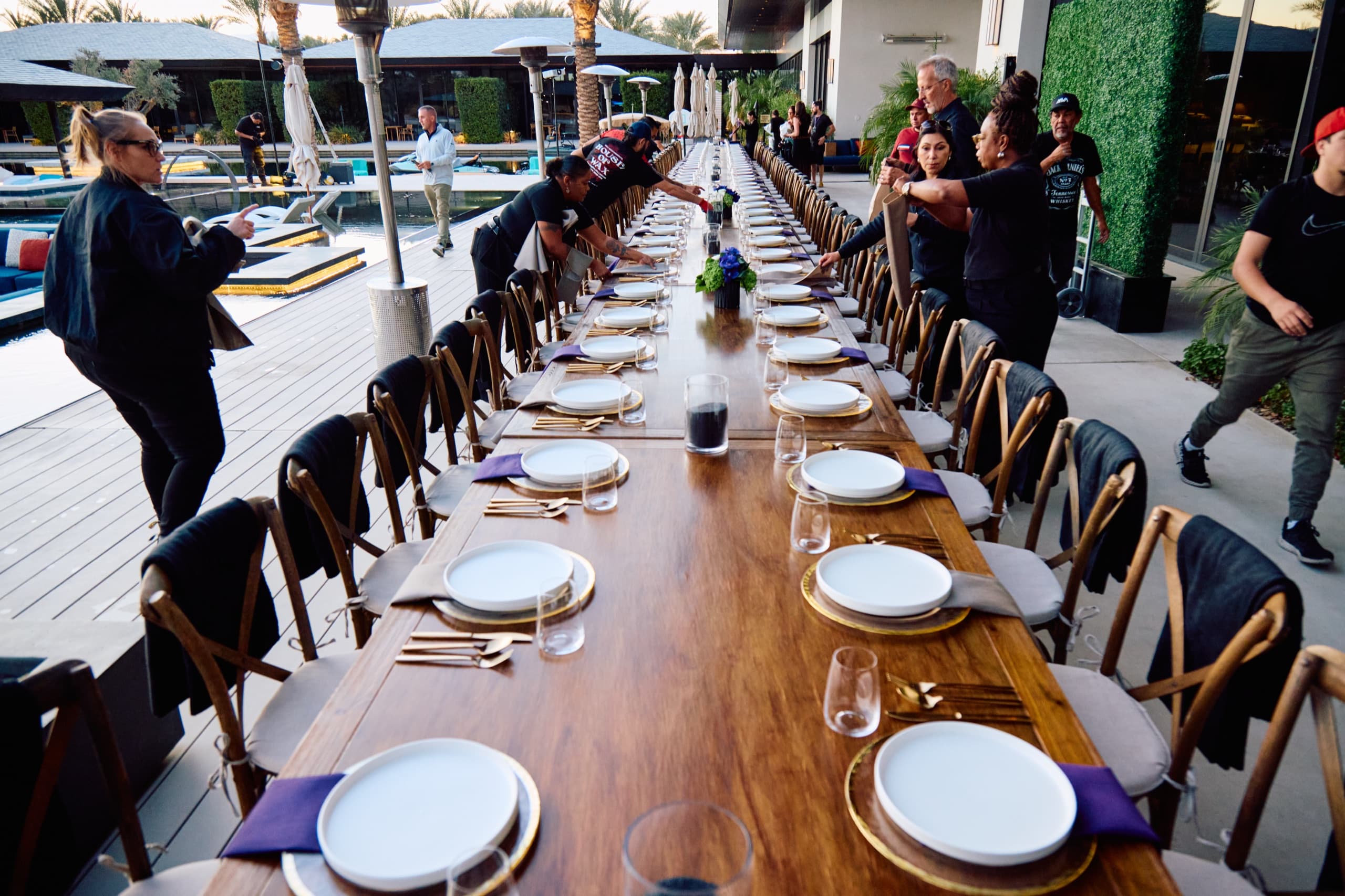 The long dinner table set with white plates beneath the palms at Zenyara Estate.