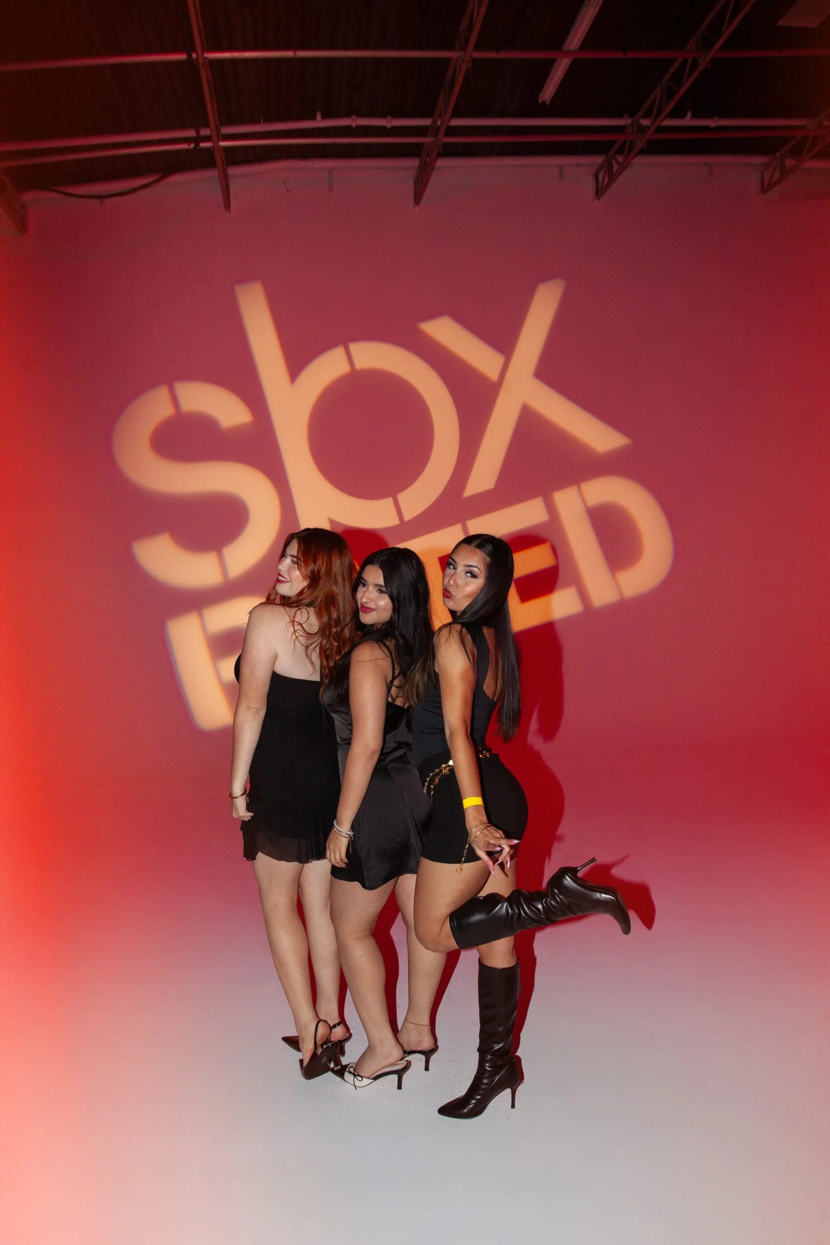 Three guests dressed in black posing together against a glowing red backdrop