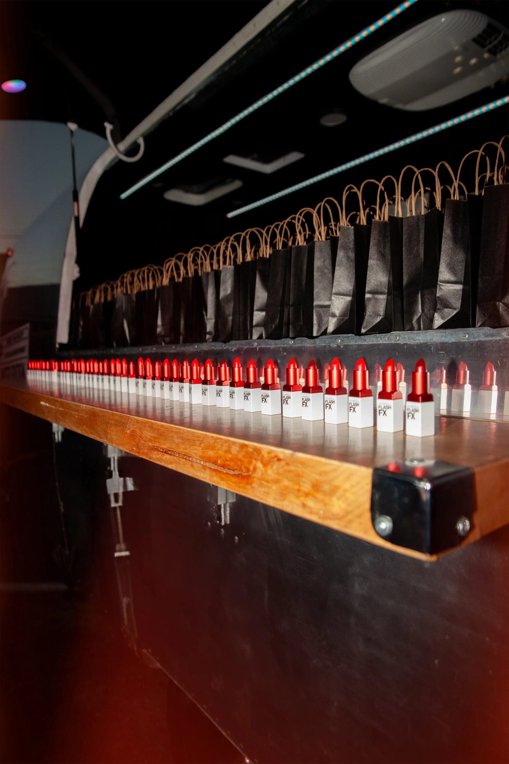 A long bar counter lined end to end with lipsticks under low red light