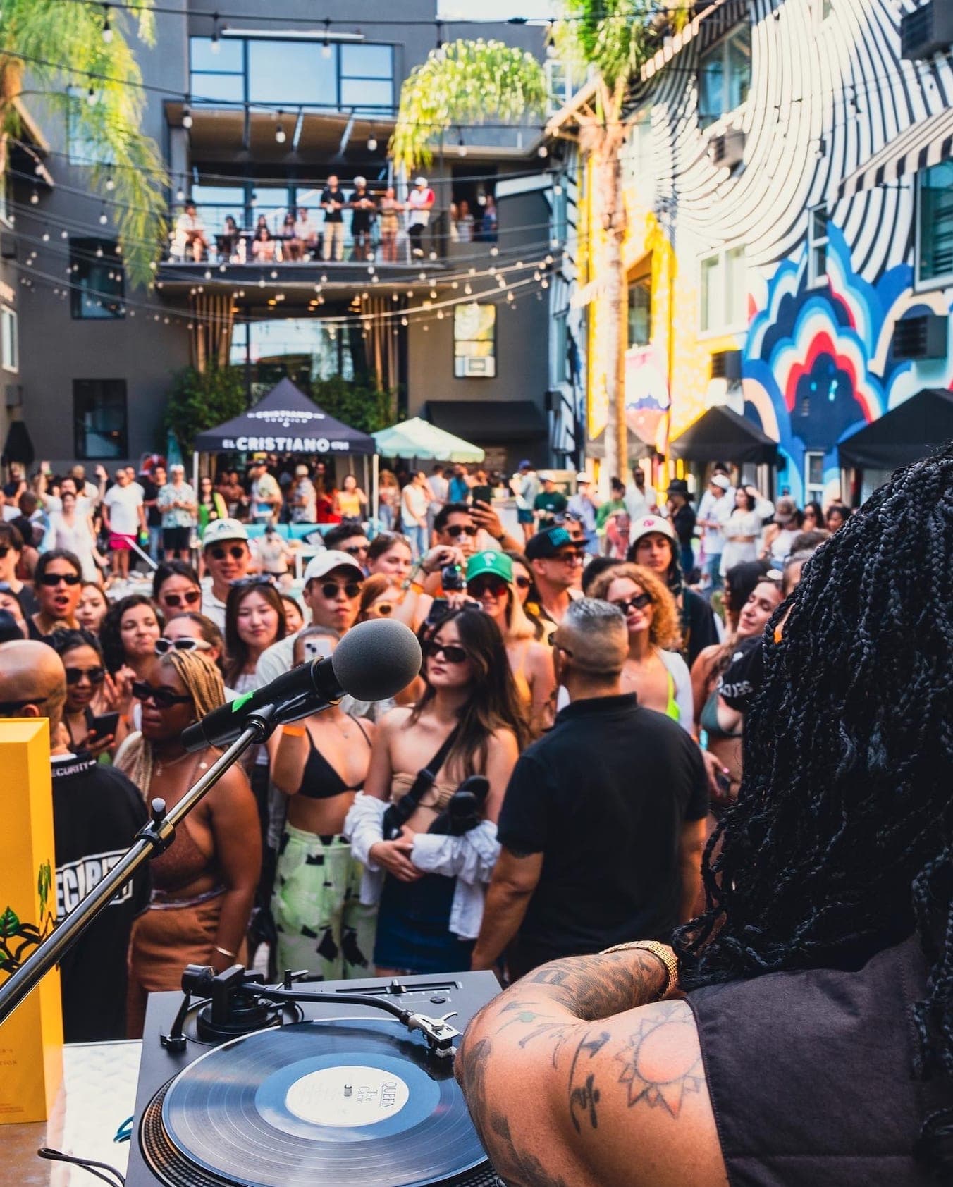 The view from behind the turntables across a shoulder-to-shoulder afternoon crowd