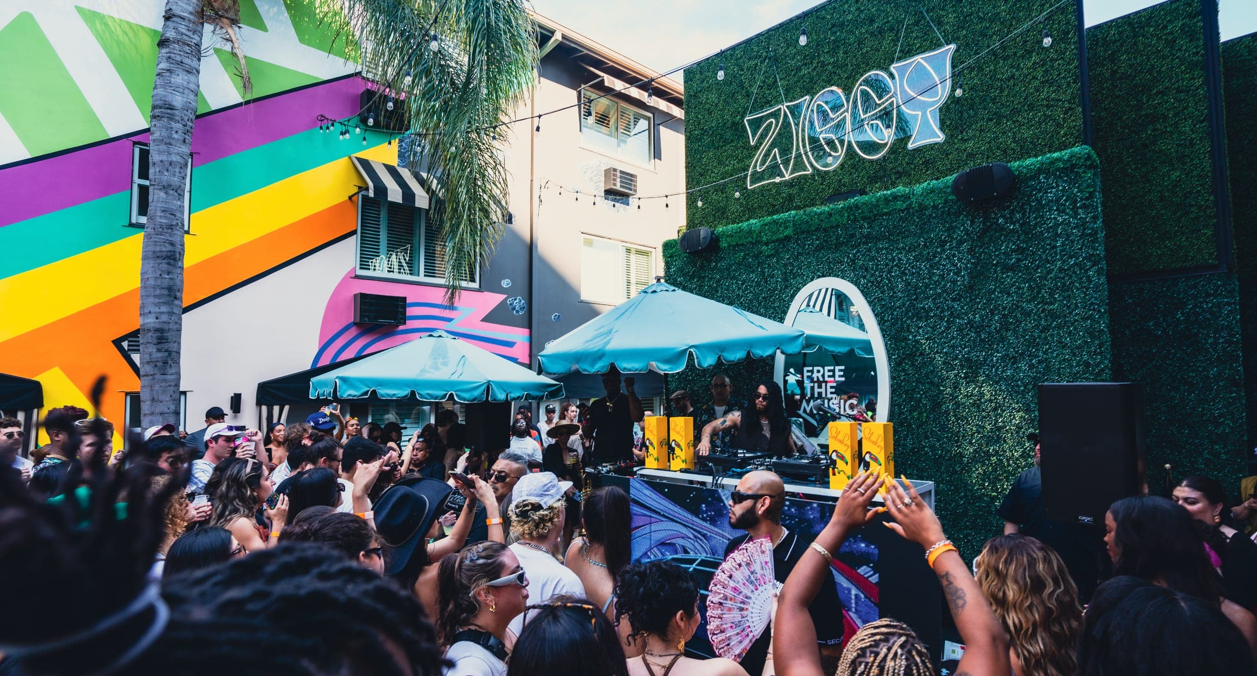 The Hotel Ziggy courtyard filled with dancers beneath painted murals and striped parasols