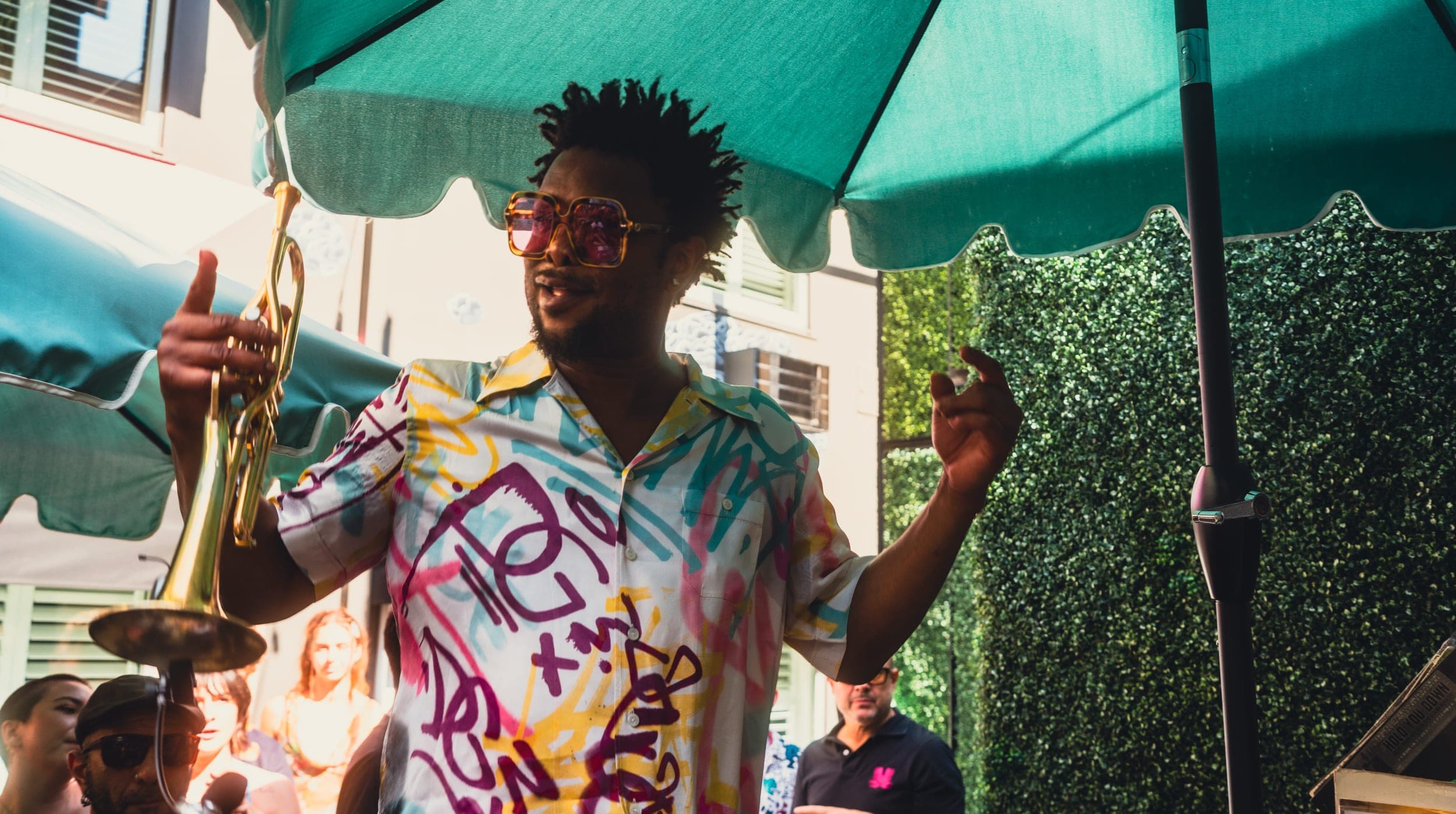 A trumpeter in a printed shirt playing over the crowd at the poolside party