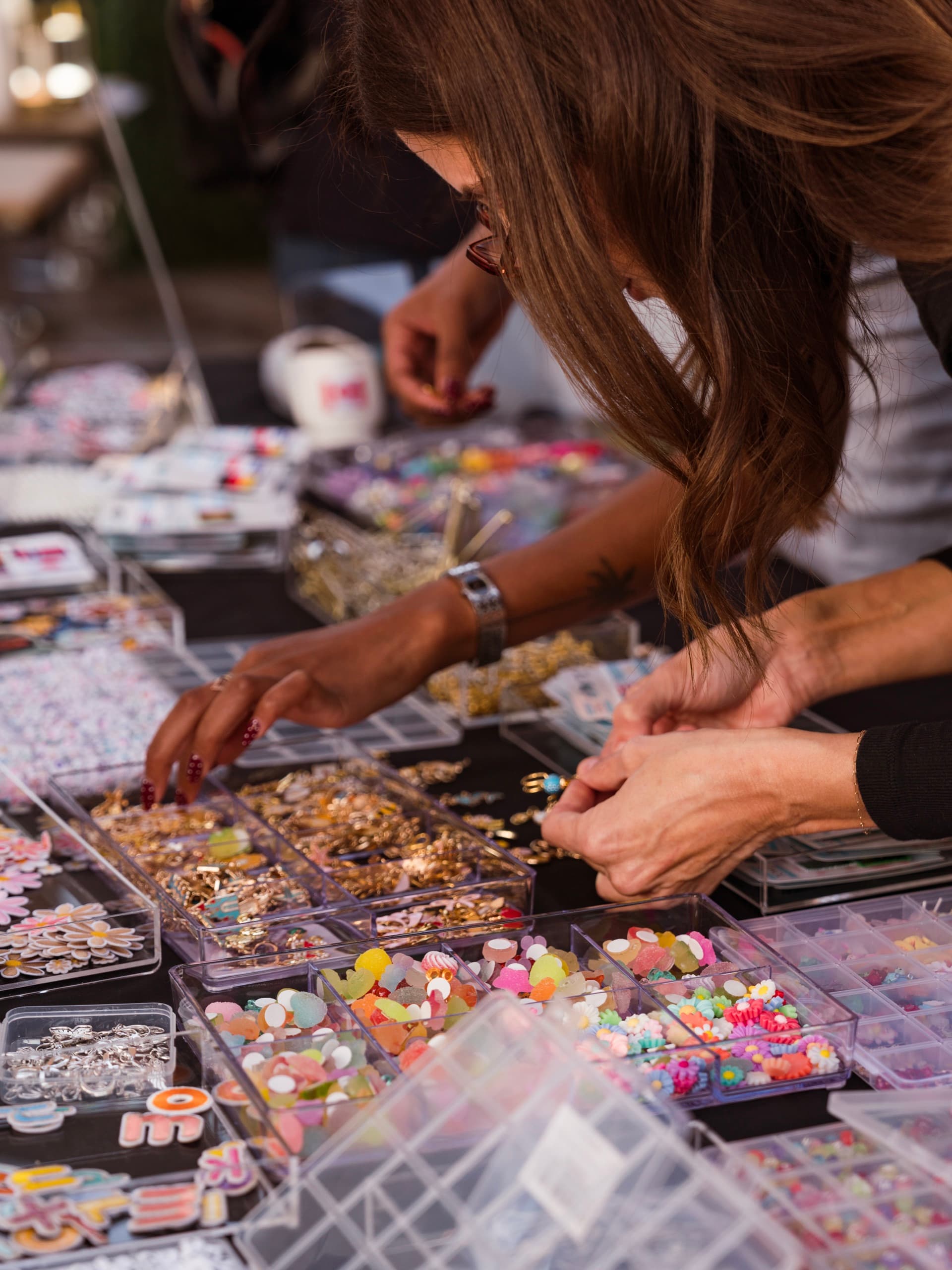 Guests choosing from trays of enamel charms, beads and gold hardware at the customisation bar.